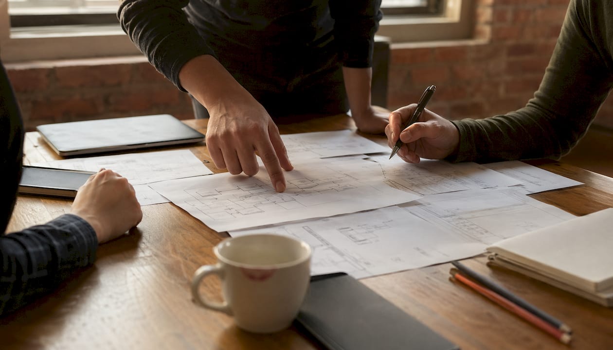 Des mains désignent un schéma de processus pendant une séance de travail en équipe.