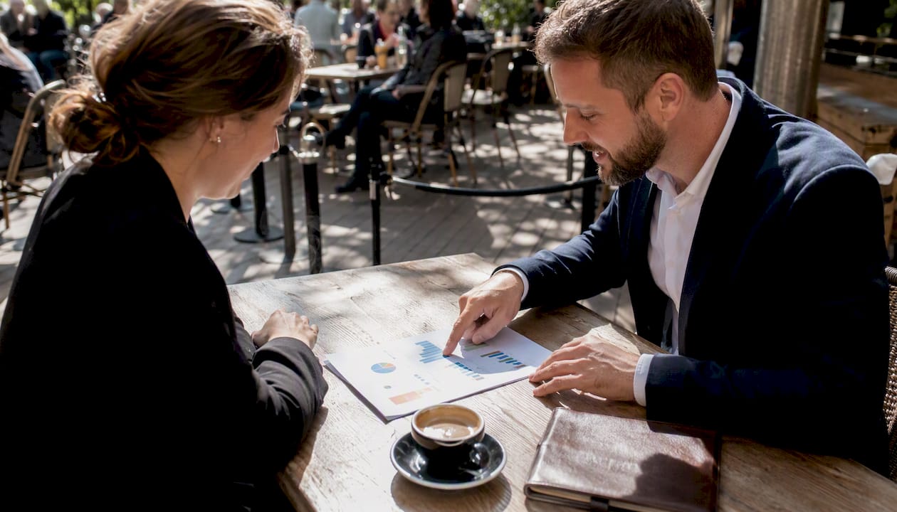 Des mains feuillettent une brochure présentant différentes activités de team building en plein air.