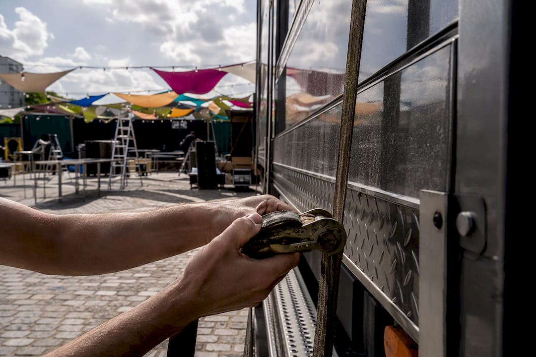 Des mains s’activent pour installer et sécuriser le food truck sur le lieu de l’événement.