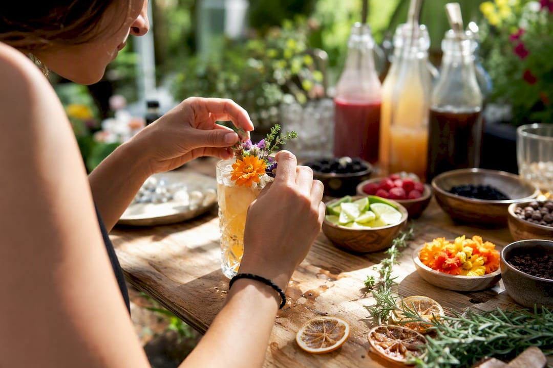 Des mains s’activent pour sublimer un verre à cocktail signature avec une touche décorative.