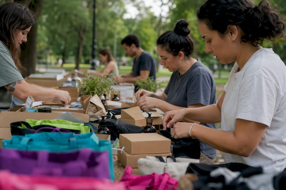 Des mains préparant des kits de dons en extérieur