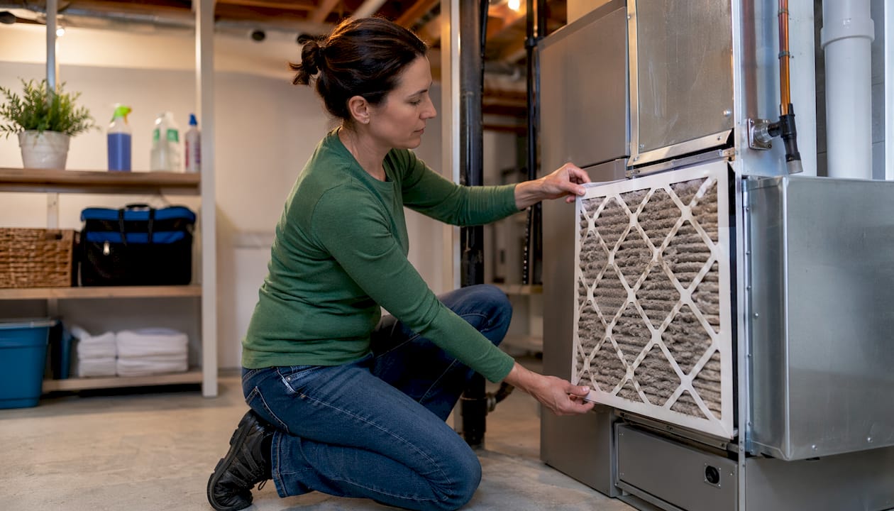 Hands replacing HVAC dirty air filter close-up