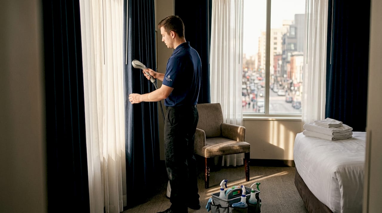 Housekeeper steaming hotel blackout curtains