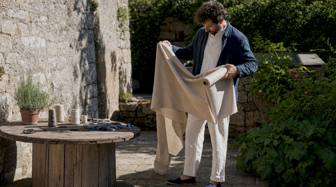 Close-up hands holding flax linen fabric in workshop