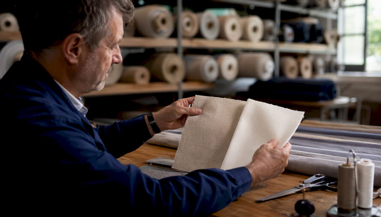 Hands comparing fabric swatches in workshop