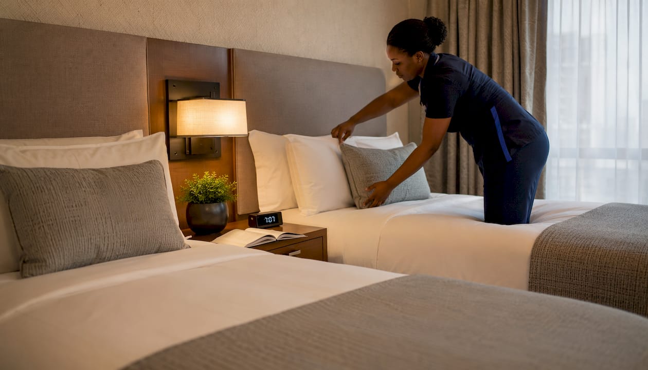 Housekeeper arranging wellness bedding in hotel room