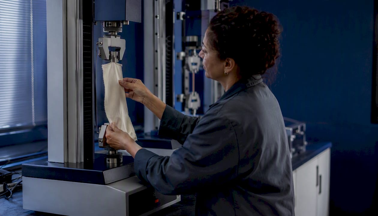 Technician testing fabric strength in lab
