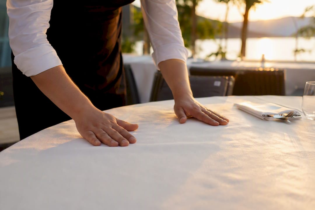 Hands smoothing hotel dining table linen