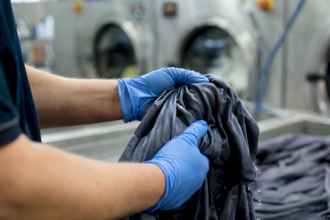 Hands testing wet blackout curtain fabric in laundry
