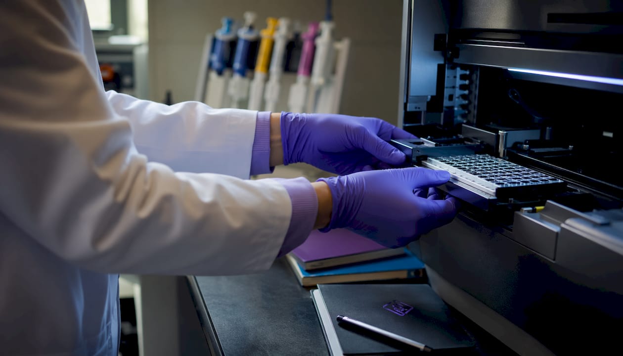 Hands loading DNA sample in sequencing machine