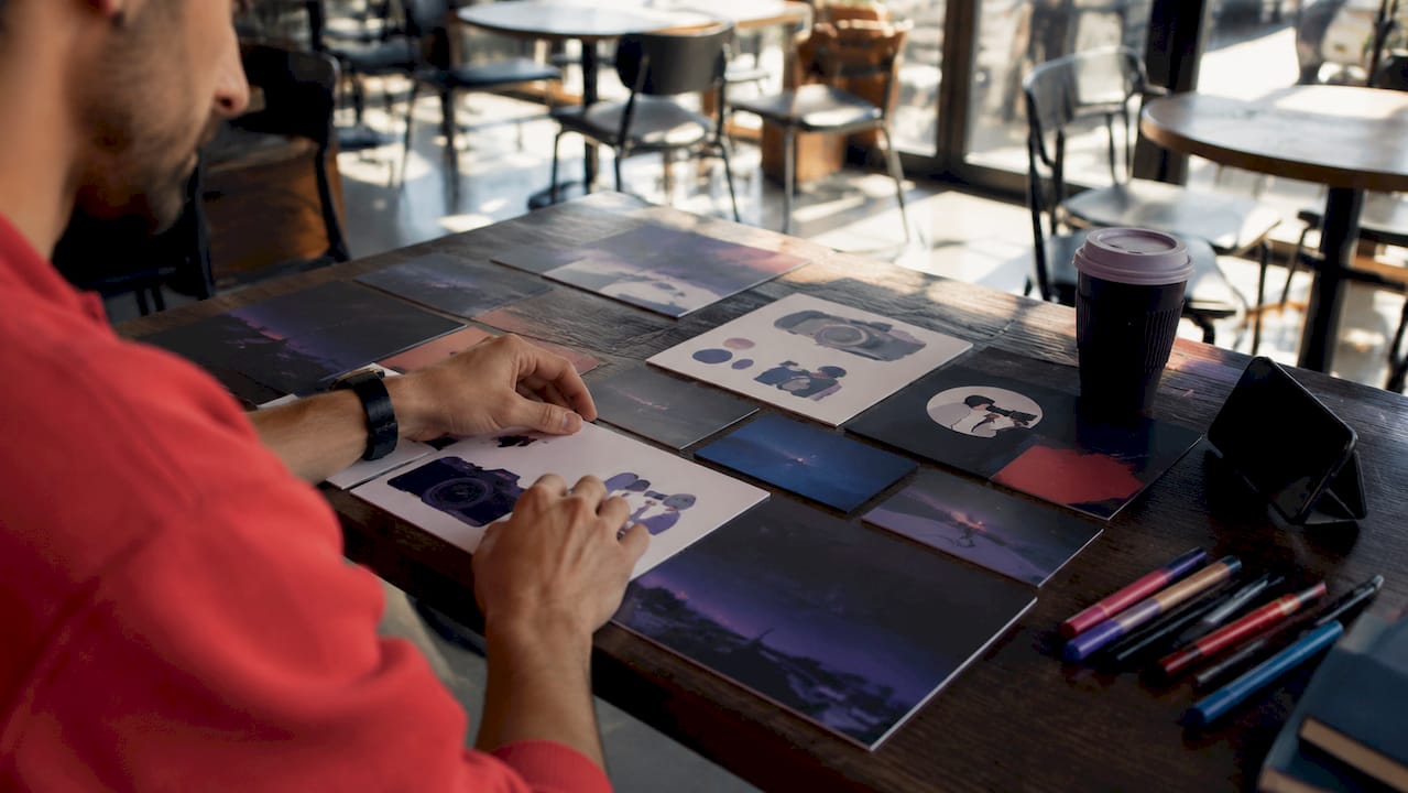 Designer hands crafting flat style branding storyboard overhead view