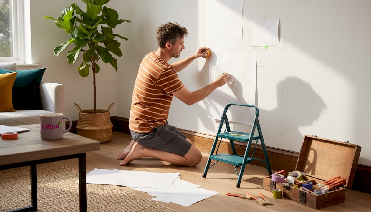 How to create a gallery wall: step-by-step NZ guide 3 Person taping paper templates for gallery wall