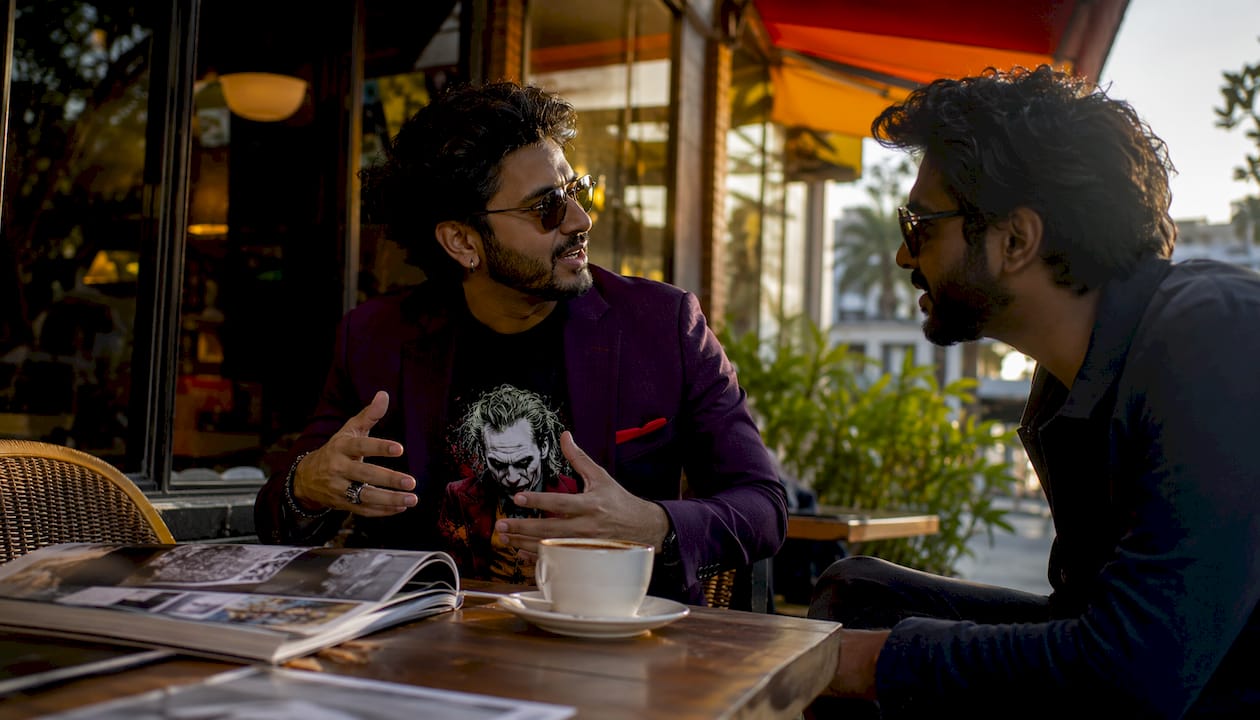 Man layering blazer over graphic tee in café