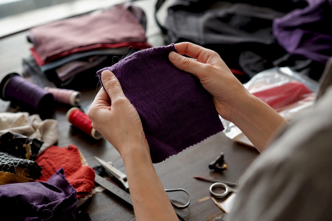 Hands inspecting purple fabric quality sample