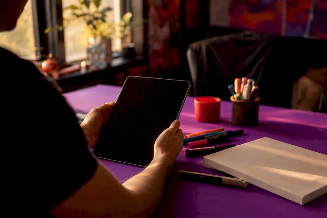 Hands holding tablet in creative workspace