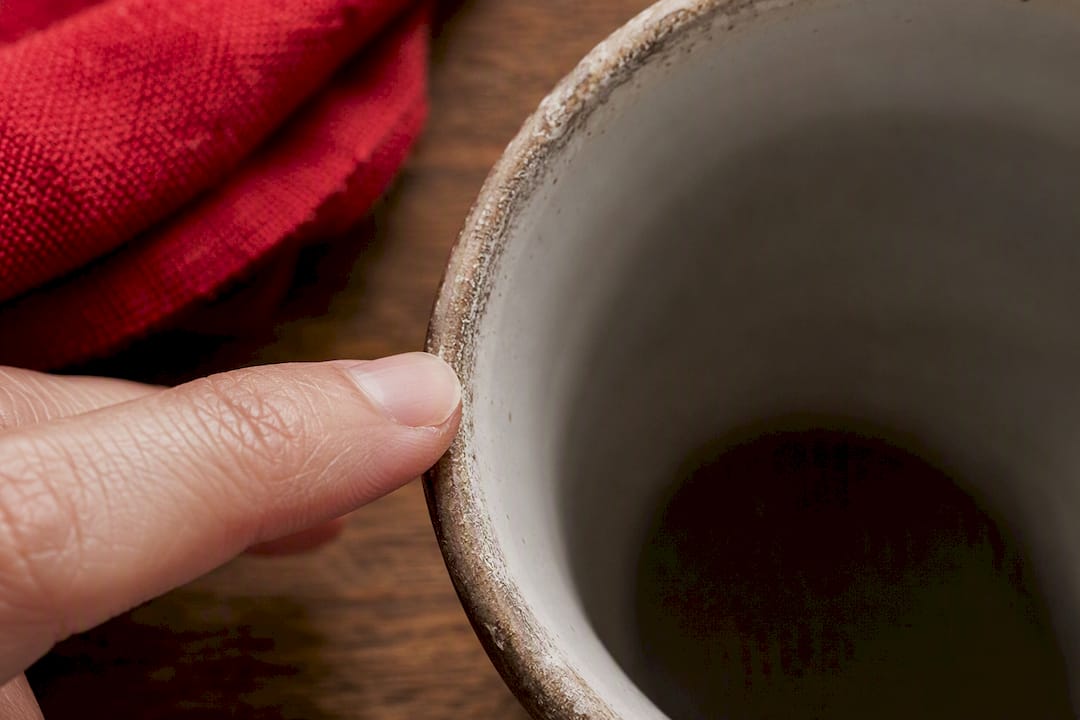 Finger checking worn glaze on mug rim