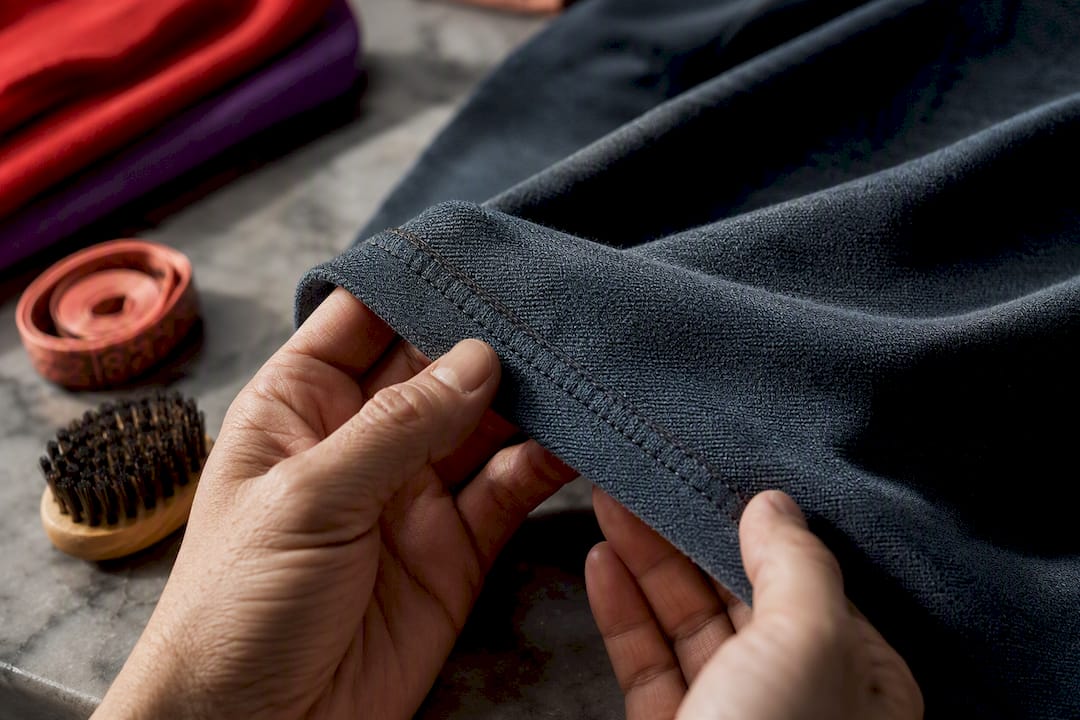 Hands inspecting shirt seam and fabric texture
