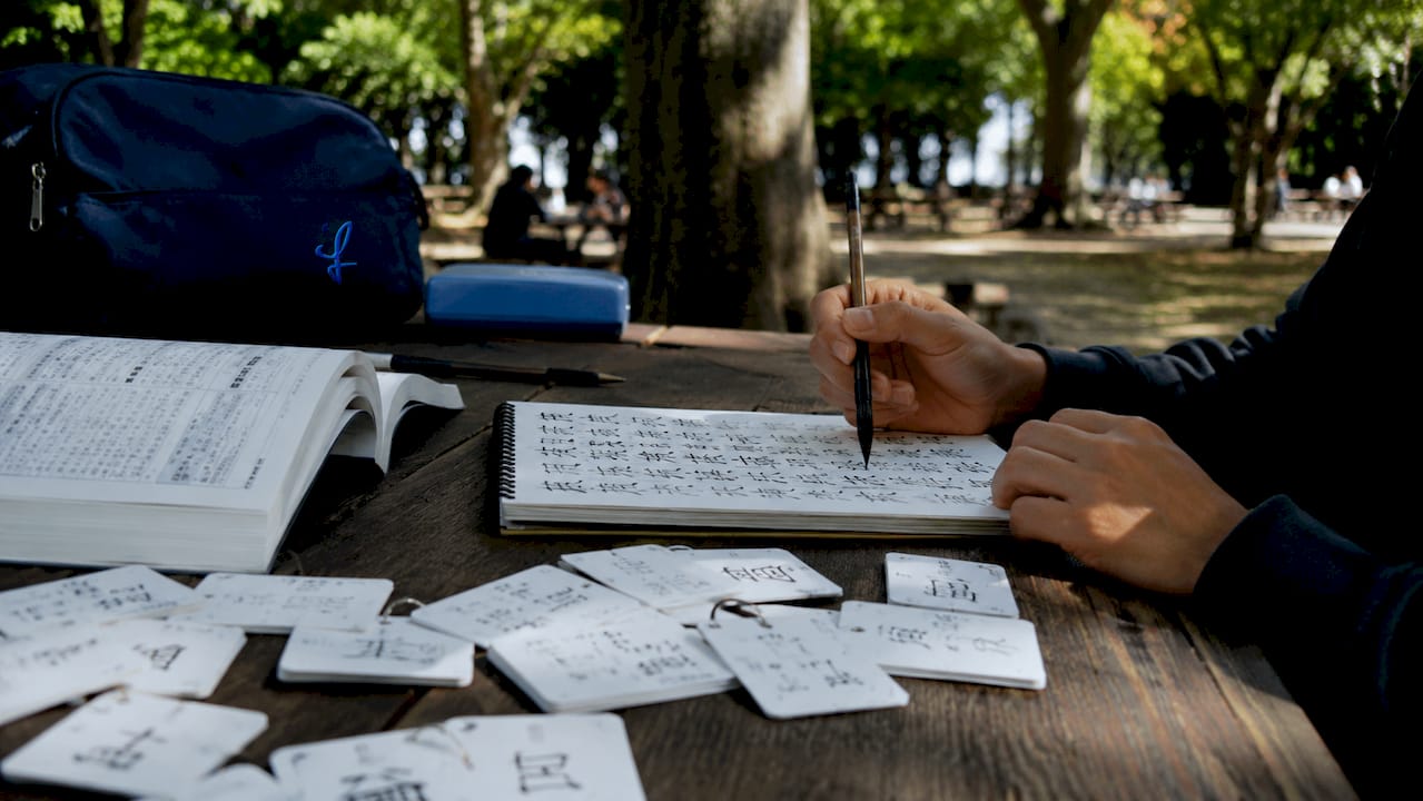 Hands taking notes with kanji and vocab study materials