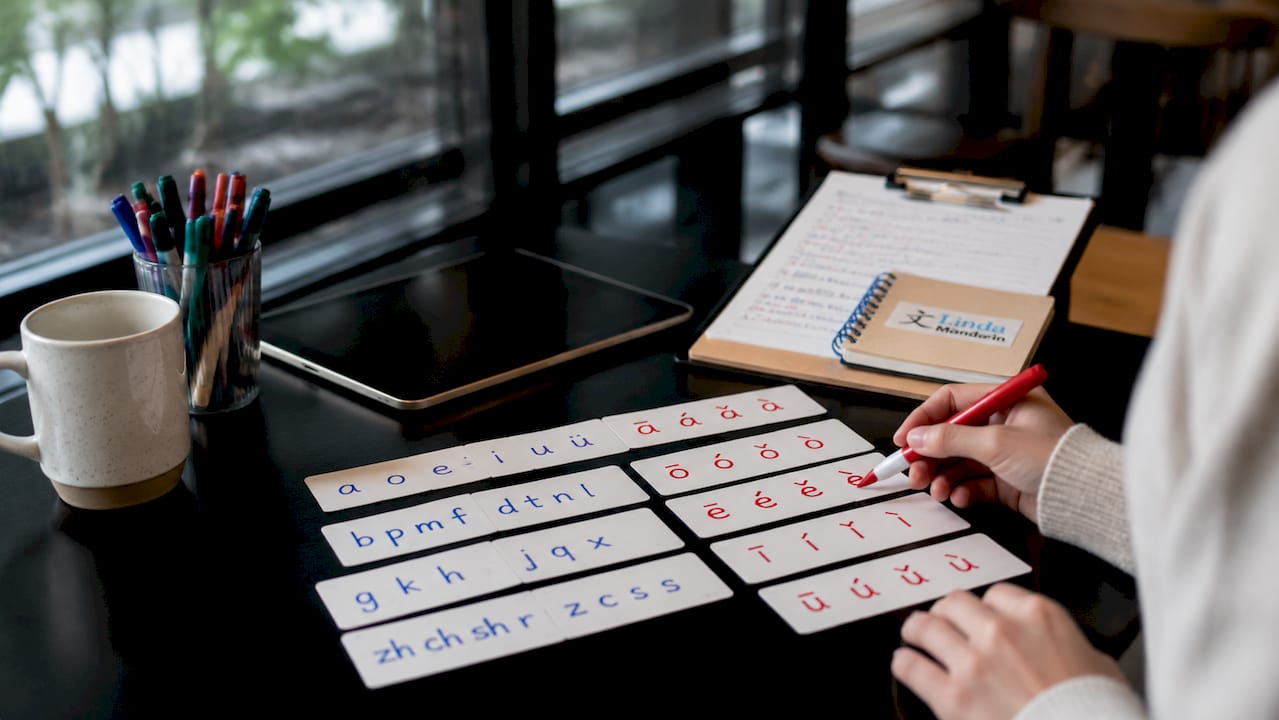 Hands writing Mandarin tones on flashcards