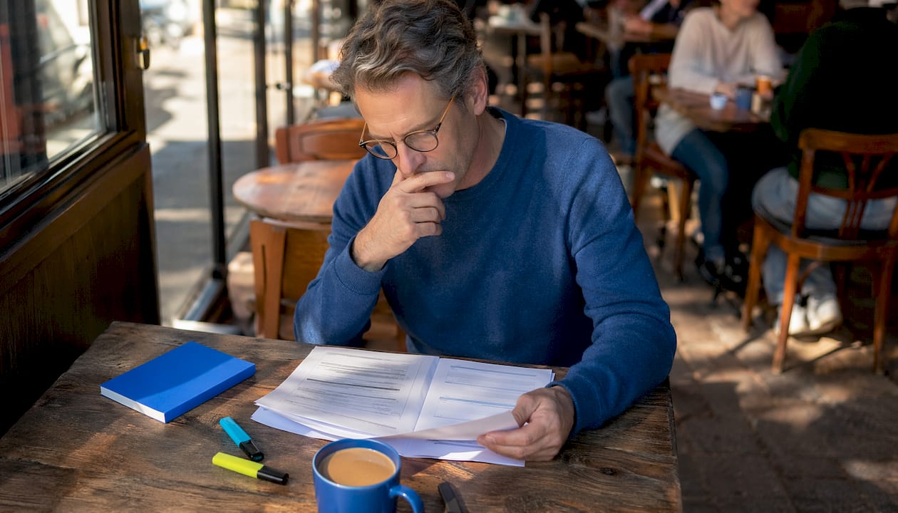 Man reviewing language learning sheets at home desk