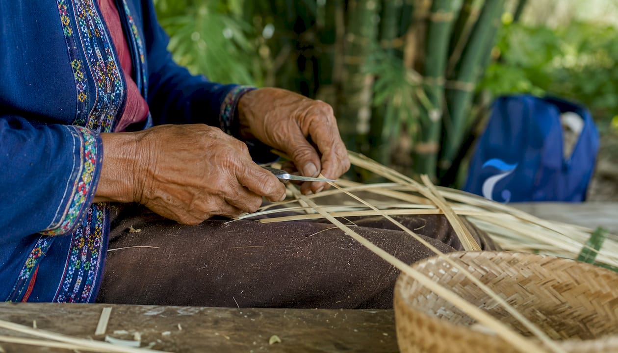 Close-up of hands preparing bamboo strips for weaving
