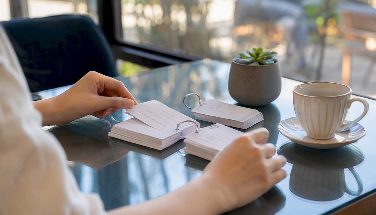 Hands reviewing sentence-level Mandarin flashcards