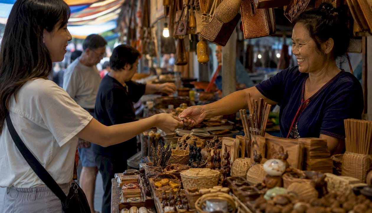 Hands exchanging coins at Thai market stall