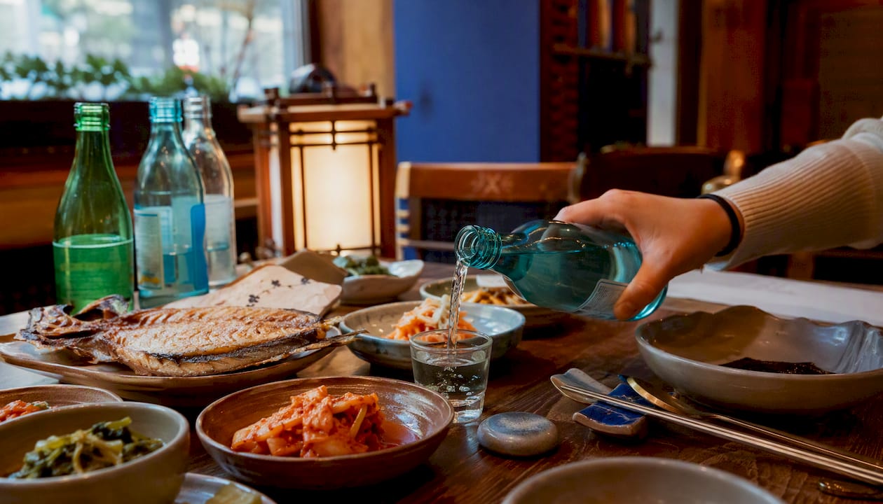 Hand pouring soju at Korean dining table
