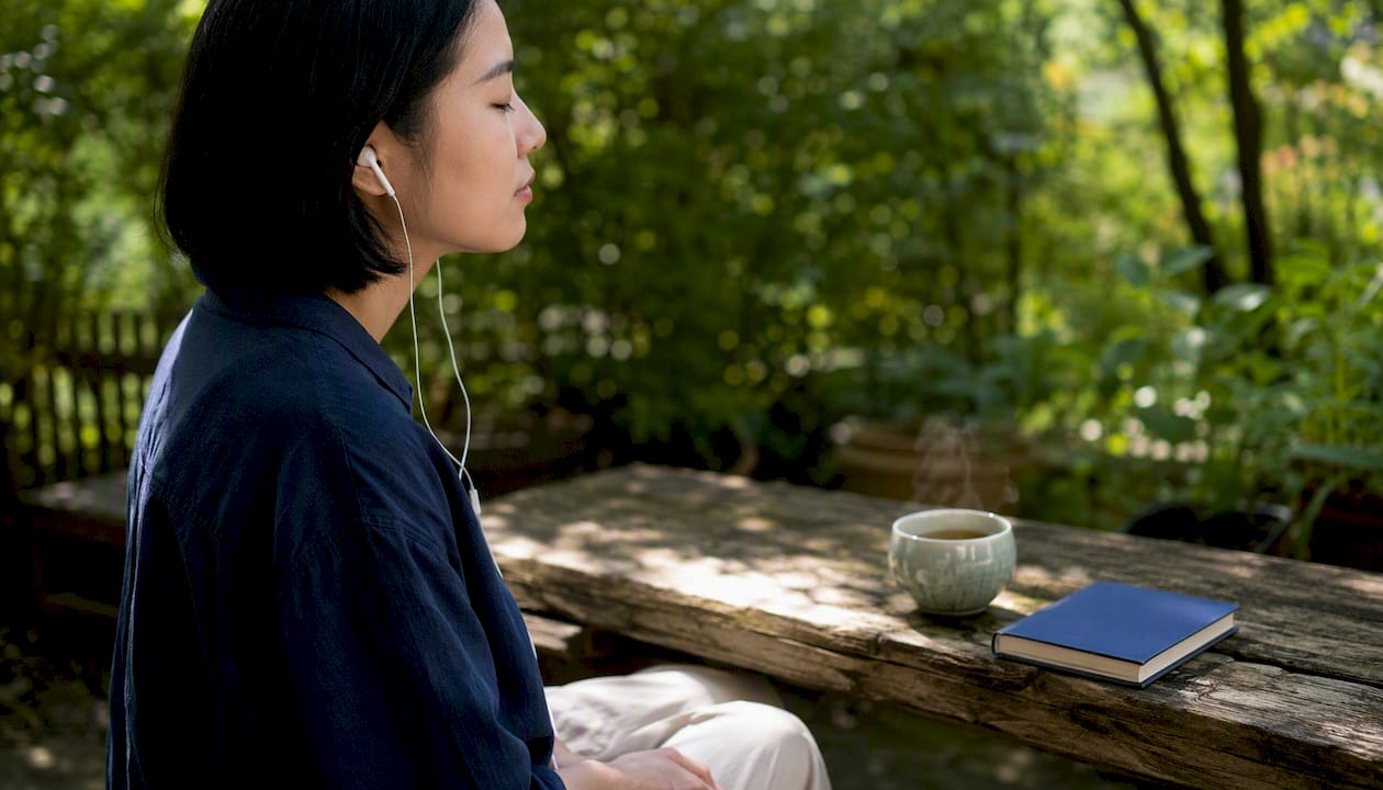 Adult learner wearing earbuds practicing listening