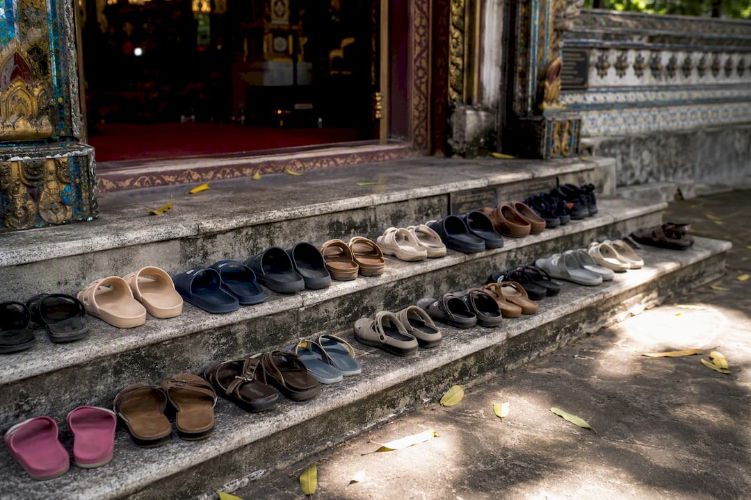 Pile of sandals outside Thai temple entrance