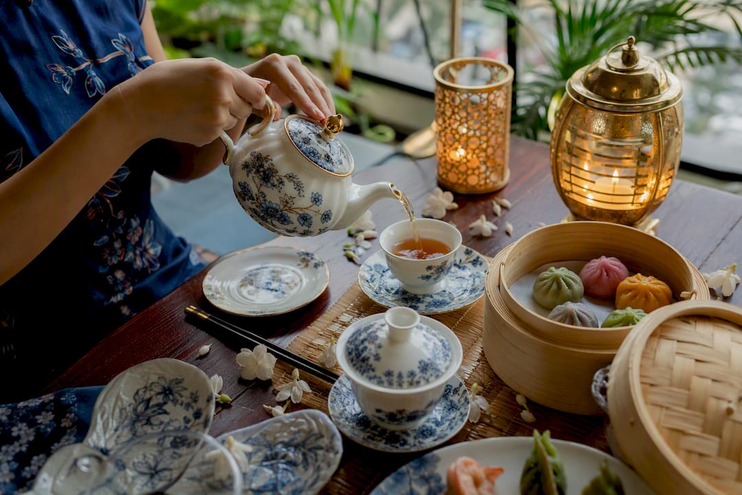 Hands pouring tea at Chinese dining table