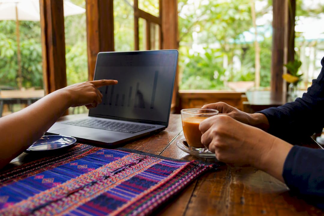Hands discussing Thai lesson pricing over laptop