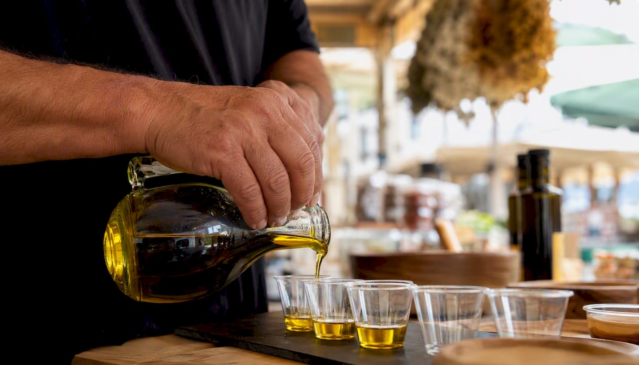 Vendor pouring olive oil at market stall