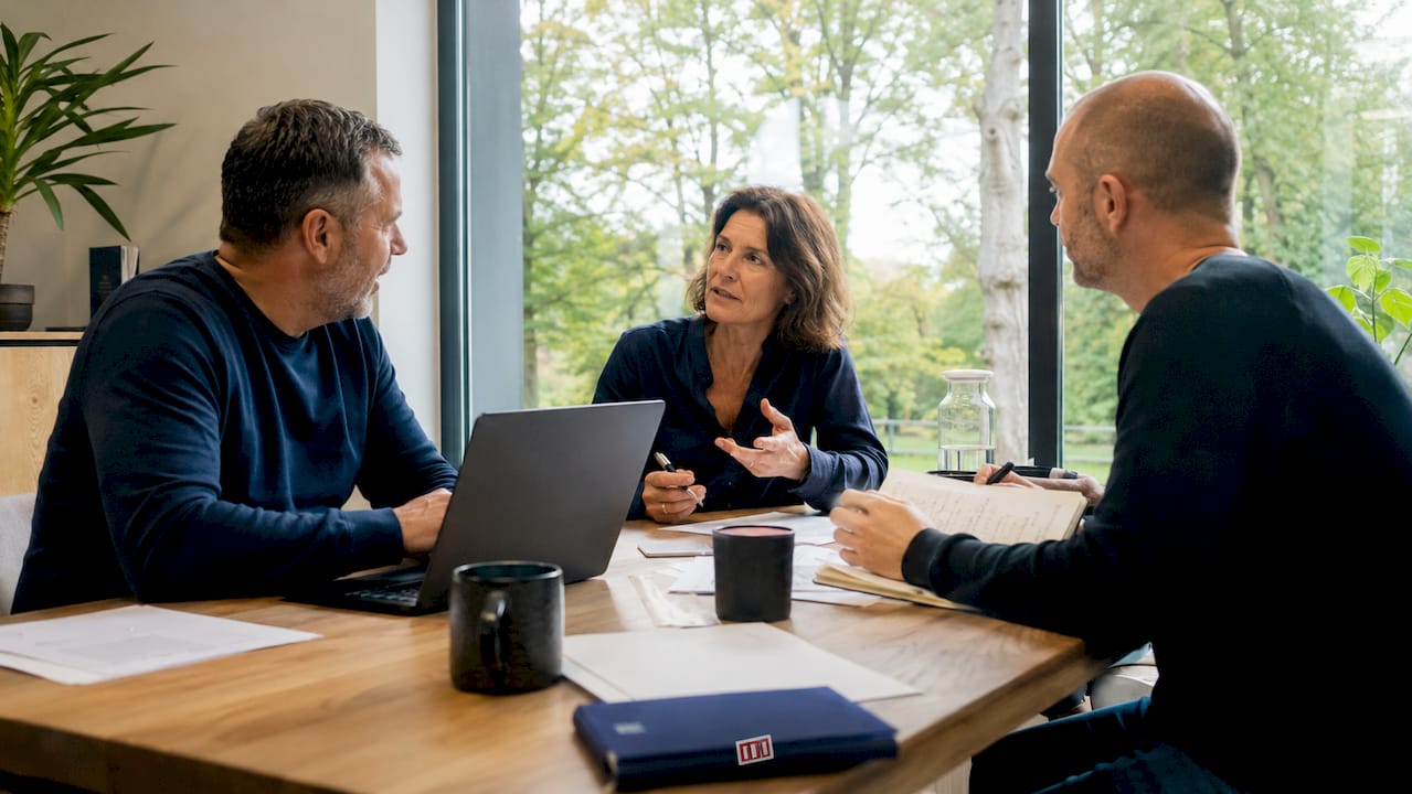 Drei Fachkräfte tauschen sich in einem zeitgemäßen Meeting über die Herausforderungen und Chancen von Digital Leadership aus.