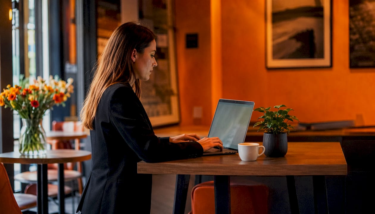 Fleißige Hände tippen auf einem Laptop in einem modernen Coworking-Bereich.