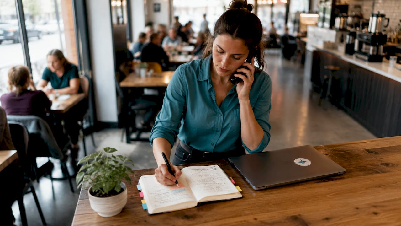 Plumber managing bookings on phone and laptop