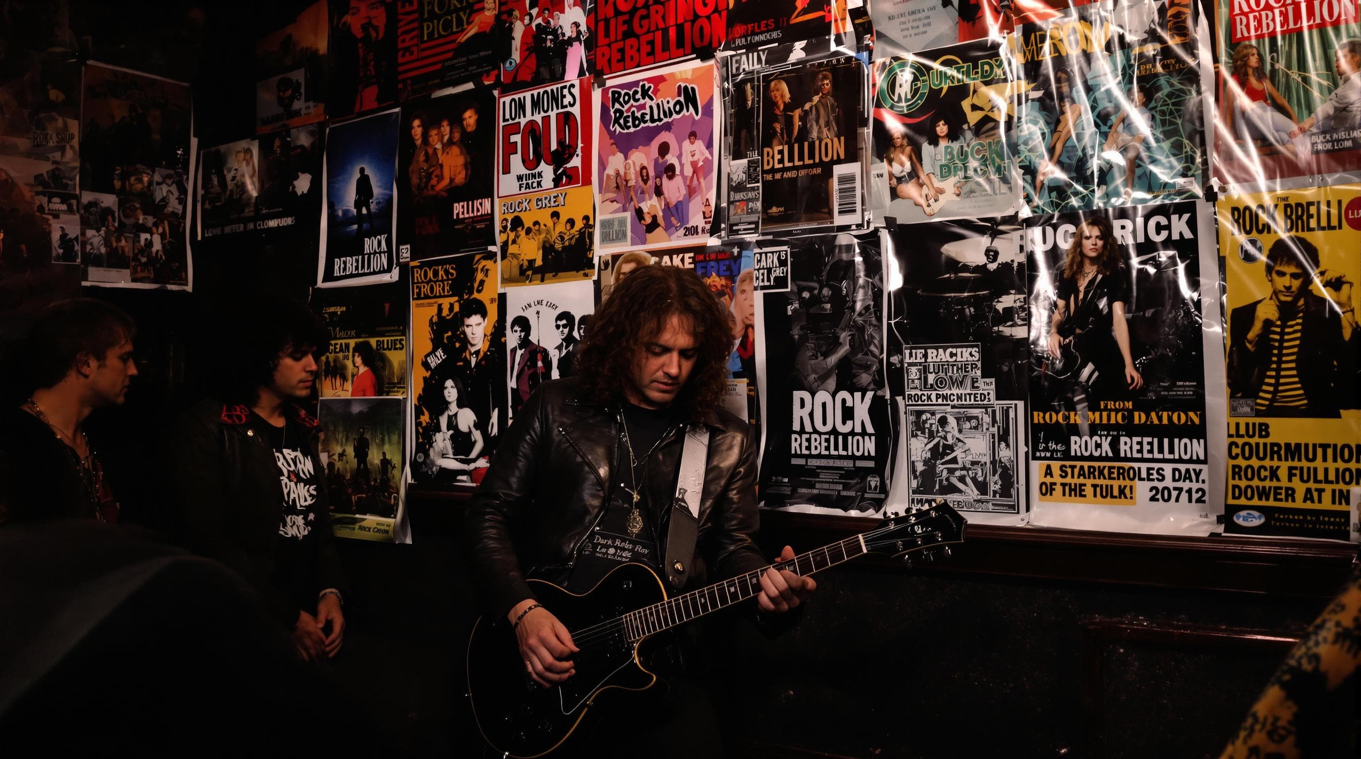 Musician in biker jacket backstage with rock rebellion posters