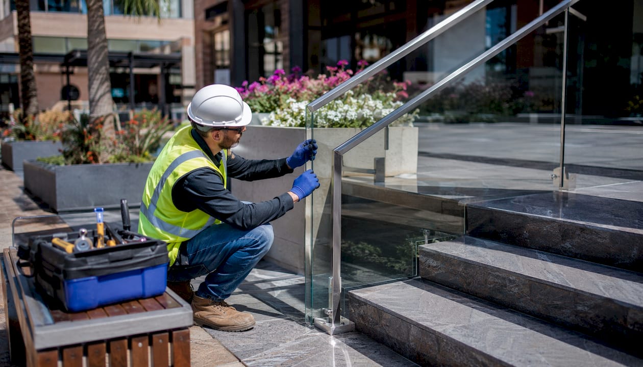 Technician inspecting commercial glass railing installation