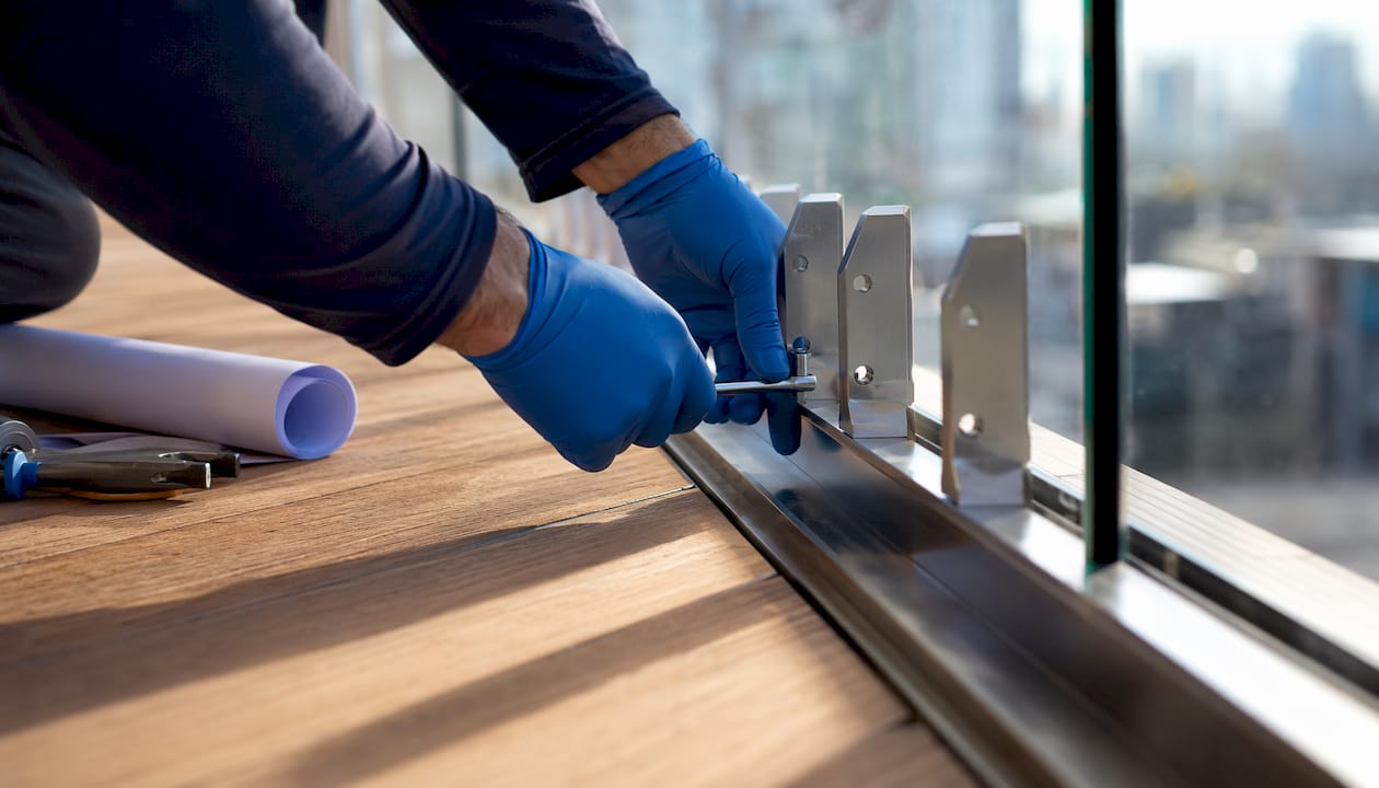 Technician installing anchors on glass railing base channel