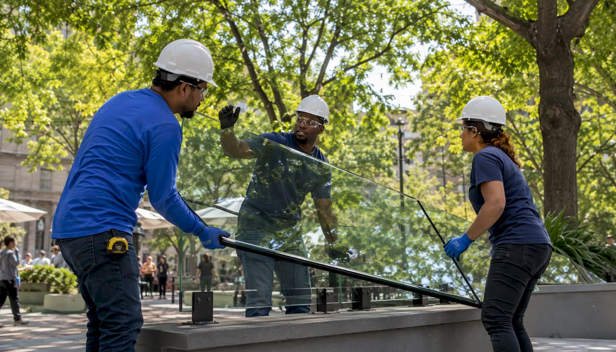 Workers lifting glass railing panel together