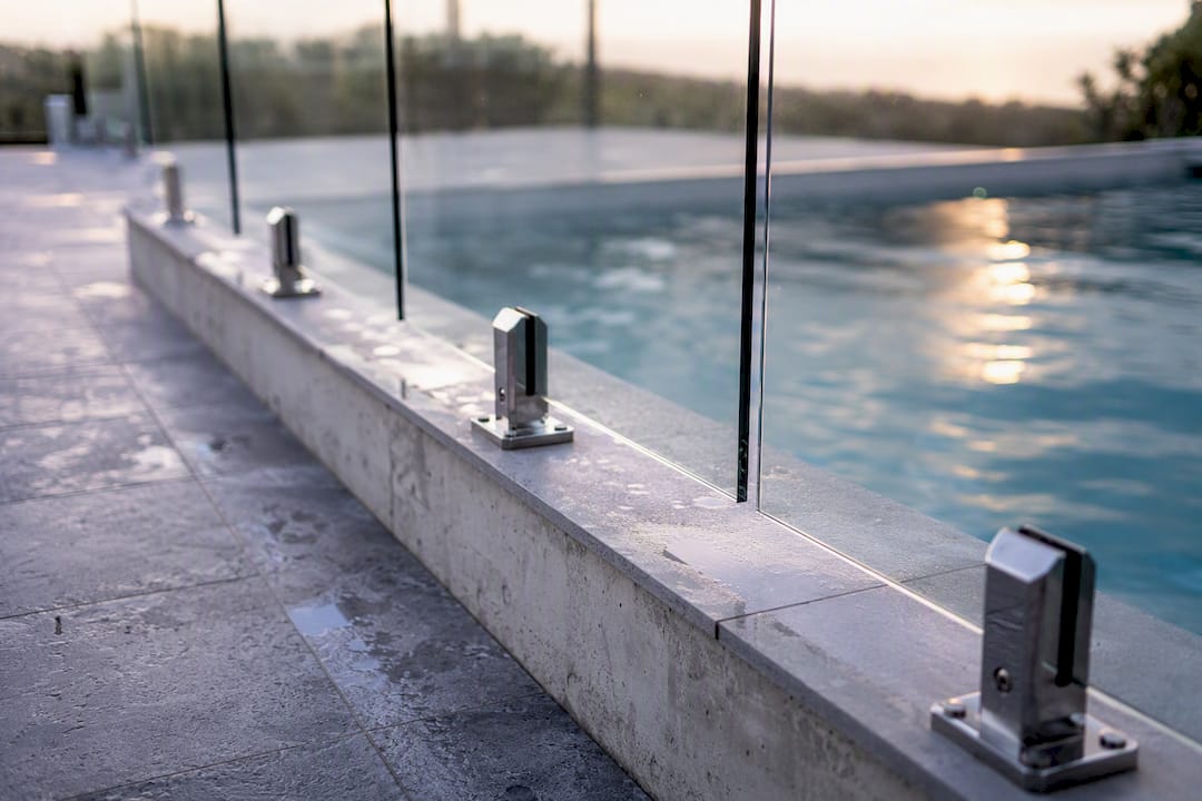 Fascia-mounted glass railing on concrete pool edge