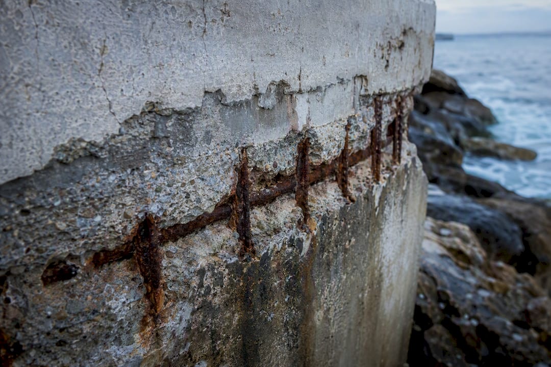 Corroded rebar and cracked concrete near ocean