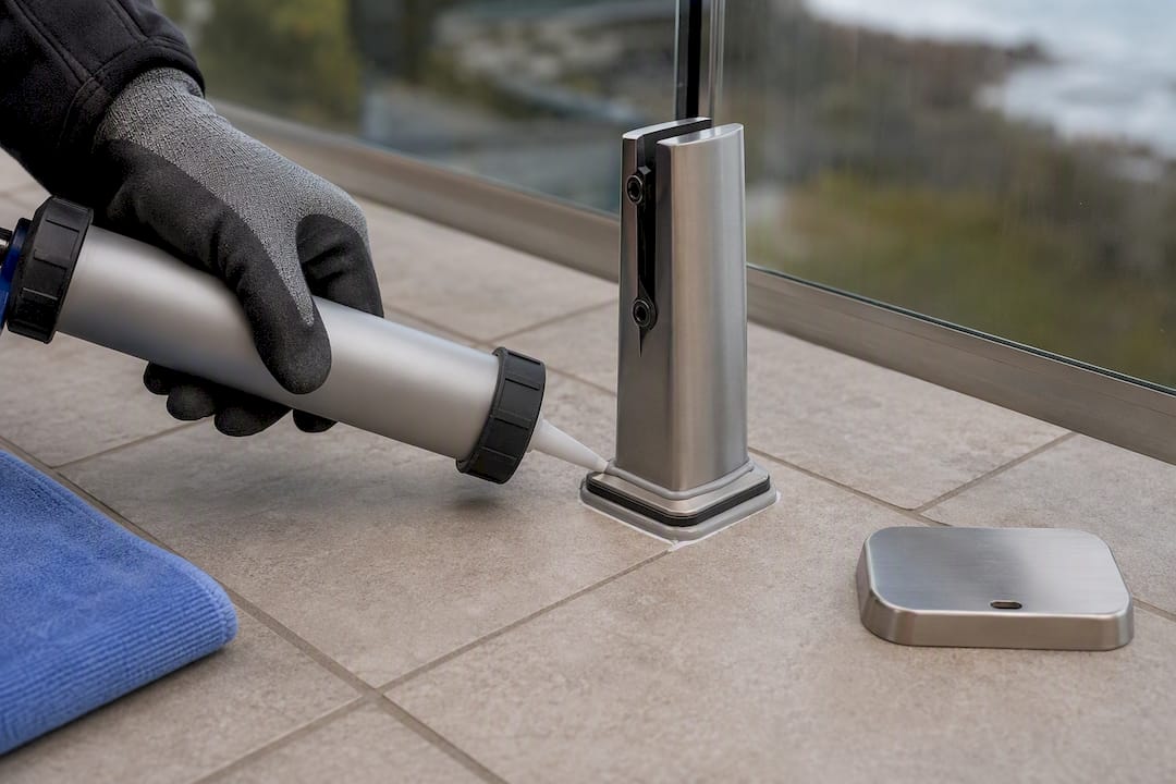 Installer sealing railing base through tile