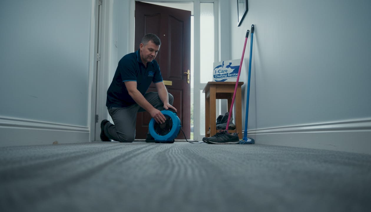 Man managing carpet drying airflow in hallway
