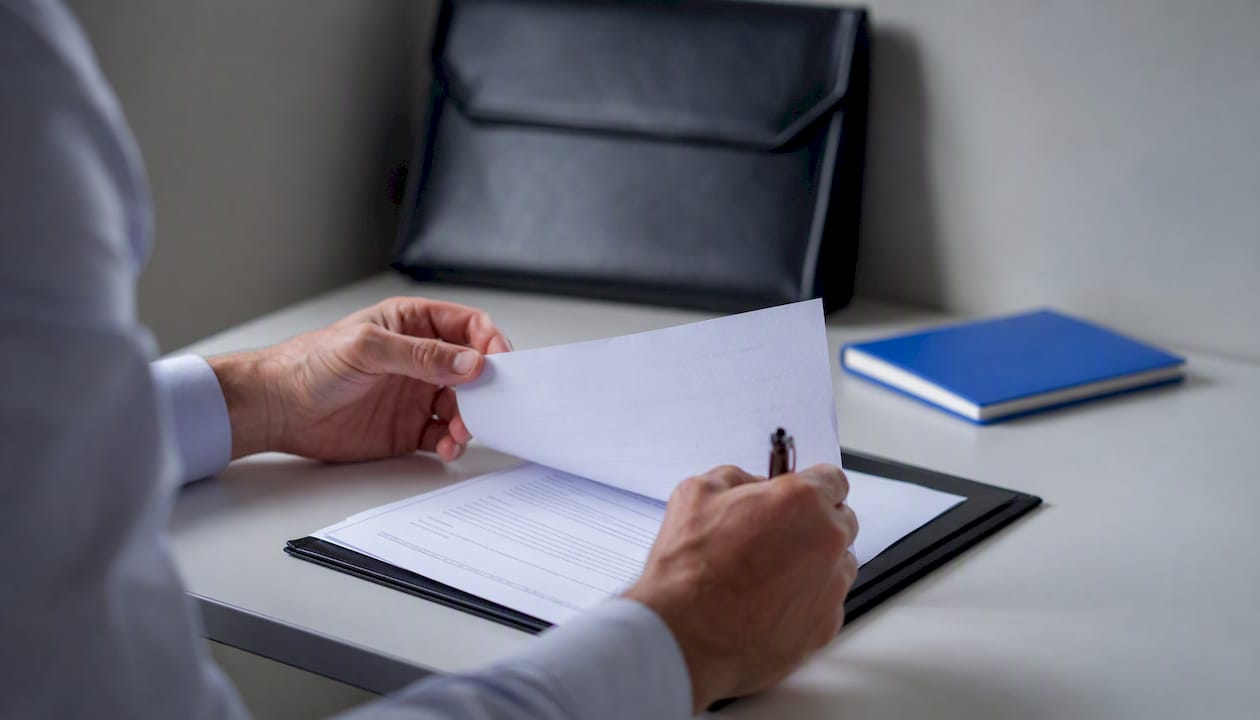 Hand placing pen near corporate documents