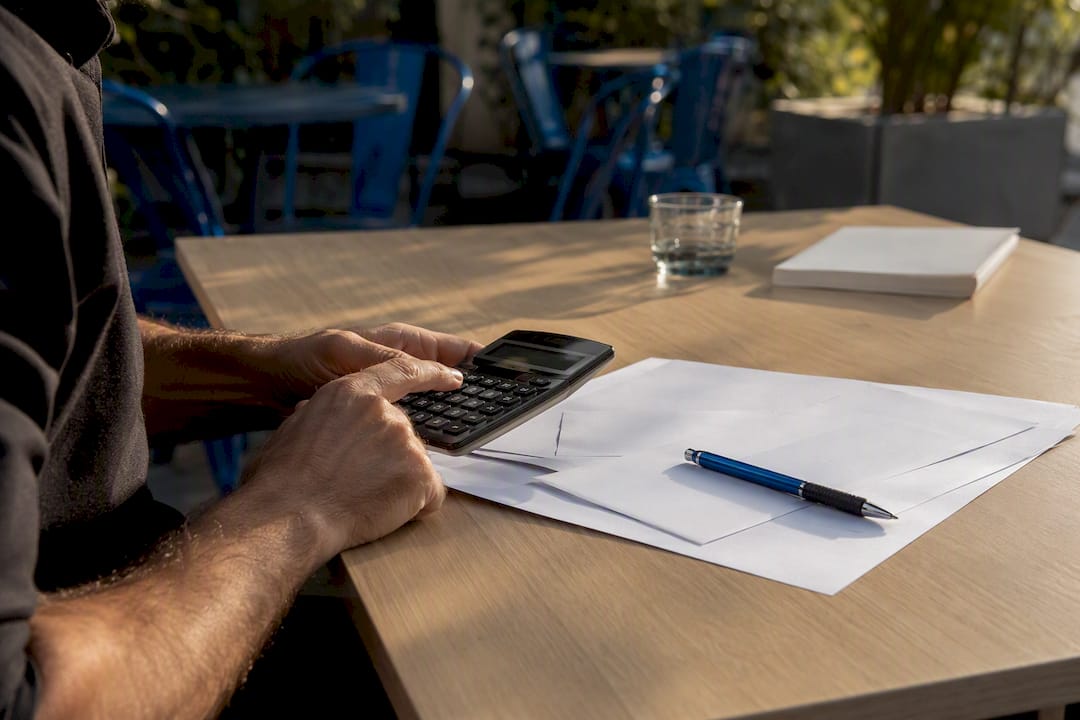 Hands calculating borrowing capacity with documents