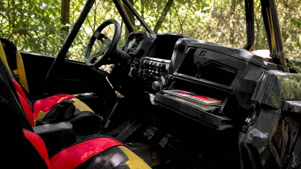 Interior cabin of a side-by-side vehicle showing controls