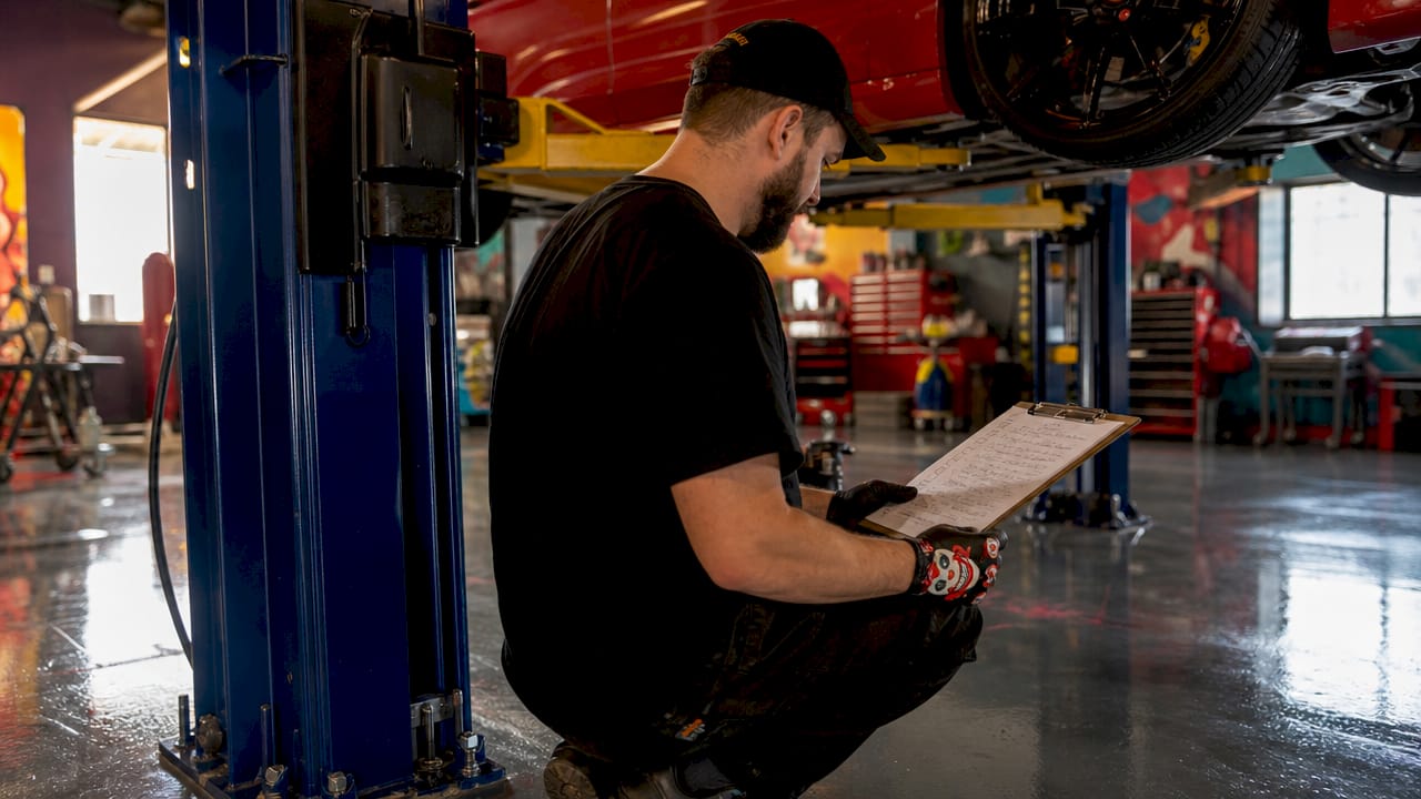 Inspector’s hands holding checklist near vehicle lift