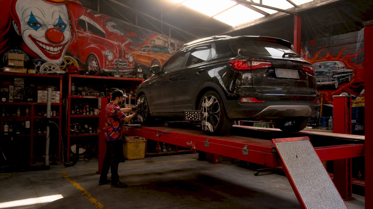 Mechanic aligning vehicle wheels on four post lift