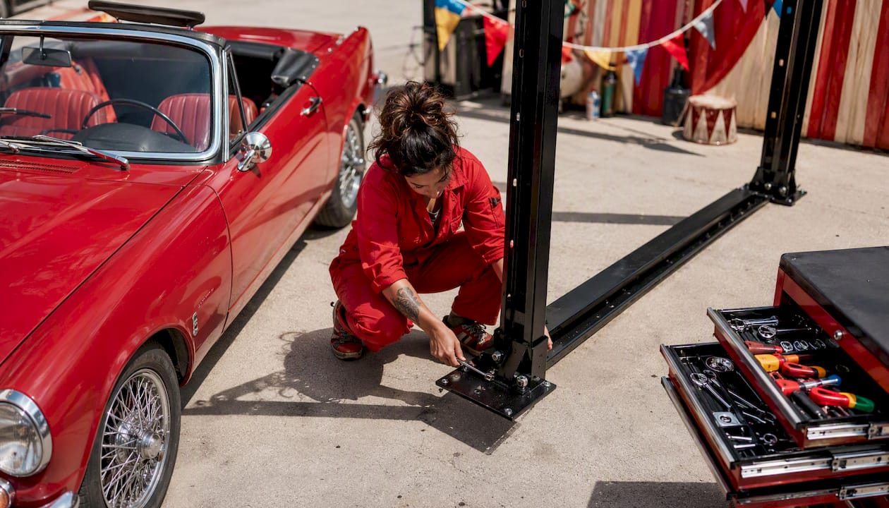 Woman assembling portable four-post car lift in garage